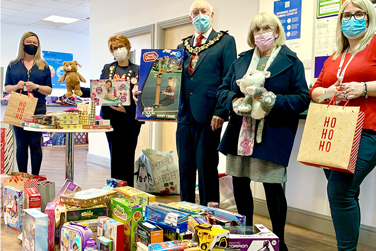 Mayor of Wirral standing behind donated christmas gifts