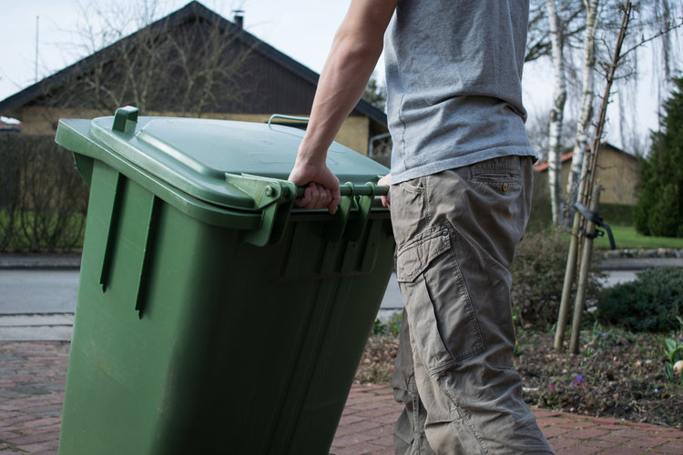Man wheeling out his green bin for collection