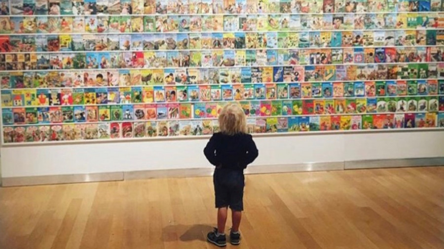 A child looking at a wall of Ladybird books