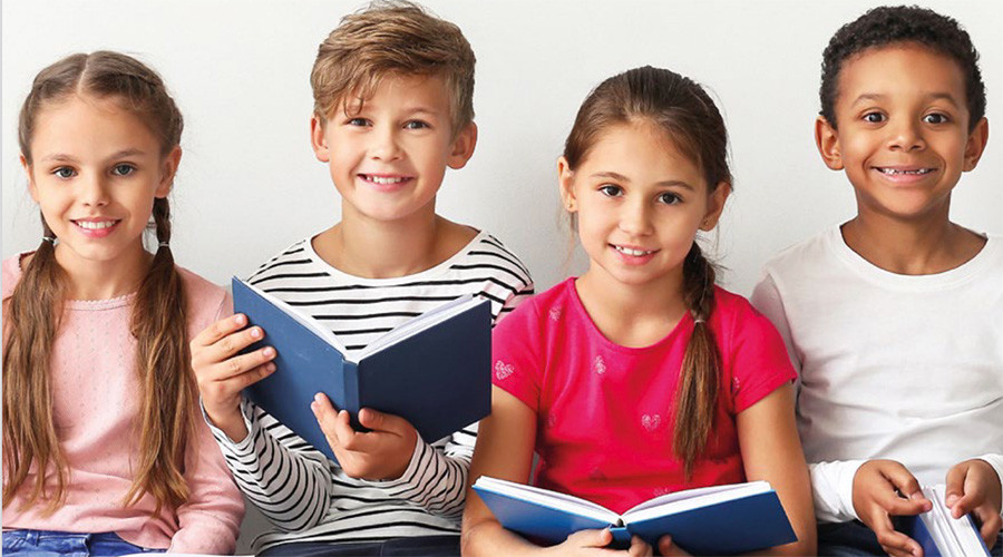 Stock image of four smiling children looking at the camera and holding open books