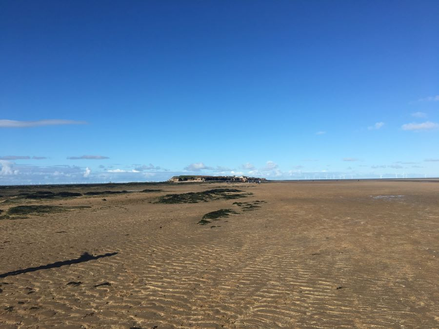 View whilst walking out to Hilbre Islands. Sand one the floor, blue skies above ad the island ahead.