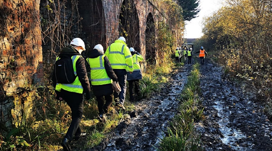 people in hi vis and hard hats walking along part of the muddy dock branch park area