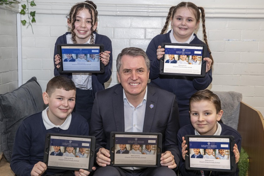 Metro mayopr Steve Rotheram sat surrounded by four school children all holding ip[ads showing their school webpage