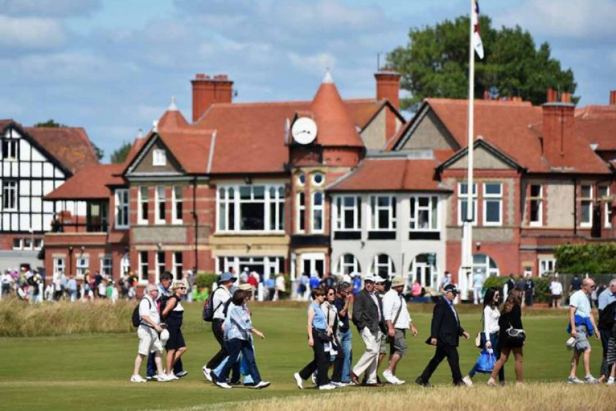 spectators waking across Royal Liverpool golf club with the clubhouse in the background 