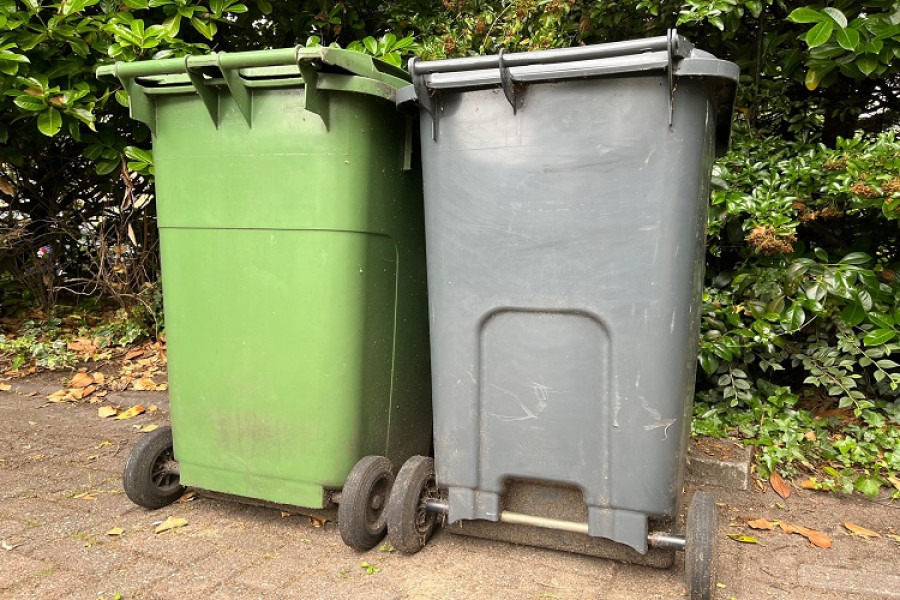 a green wheelie bin on the left next to a grey wheelie bin