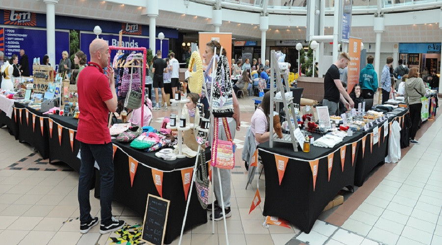 a wide shot showing traders behind desks with black tablecloths and orange bunting