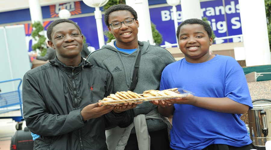 three young entrepreneurs holding a tray of cookies