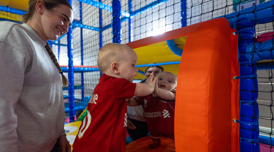 A toddler looks in a mirror in soft play area