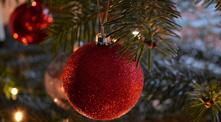 Close up of a red sparkly Christmas bauble hanging on a tree