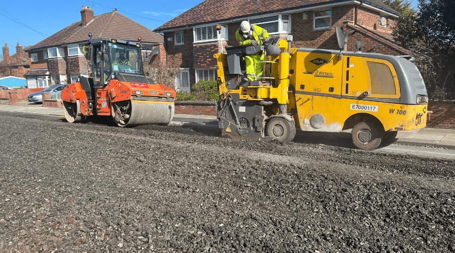 image shows roadworks underway with steamroller following a truck