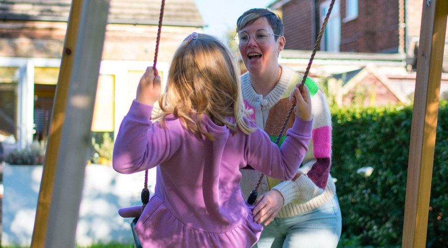 Young women pushing girl on swing