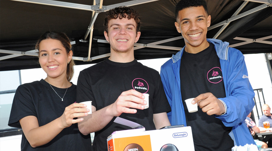 Three members of the Podwala Limited team holding out samples of their coffee