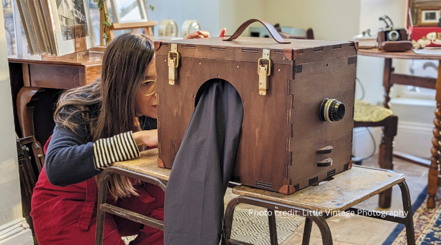 A young person peers into a vintage-style camera.