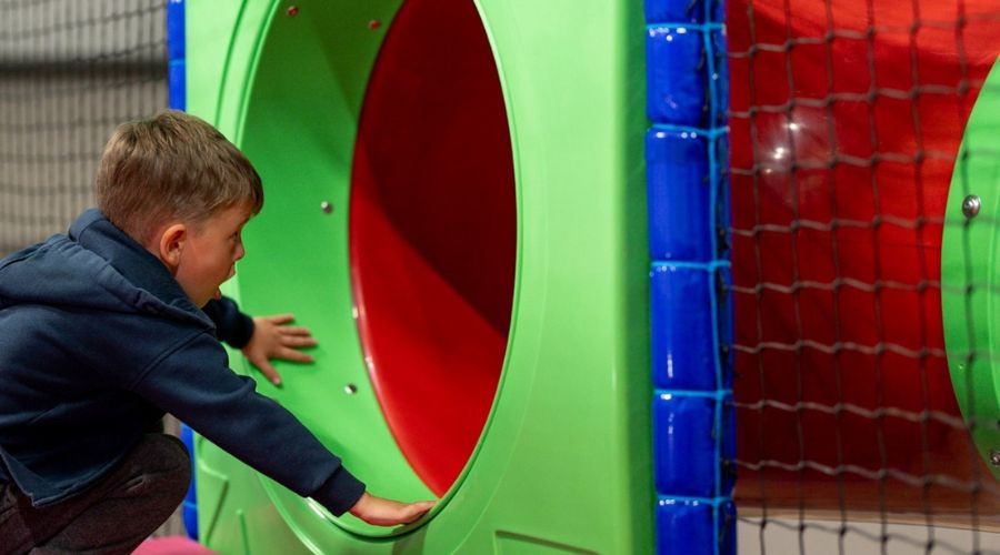 Young boy entering a brightly coloured slide