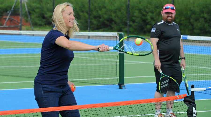 Two tennis players standing on the same side of the net on a tennis court.