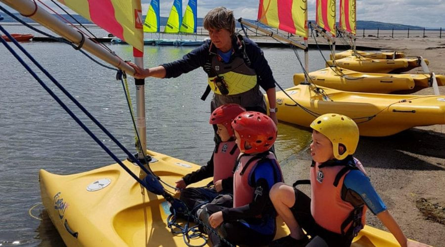 Children on a sailboat with an instructor on the lake.