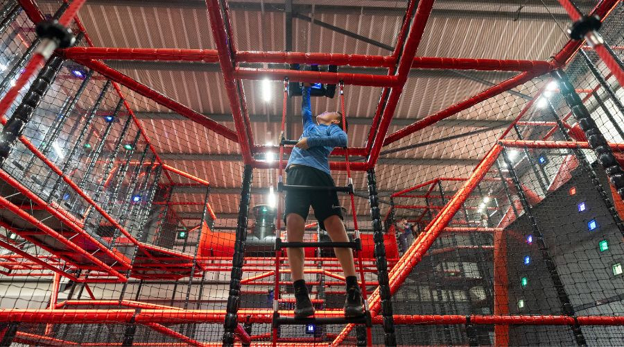 Child standing on an indoor climbing frame reaching towards a button