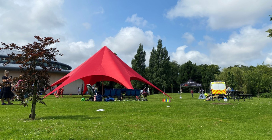 View of event taking place in the park including a red gazebo 