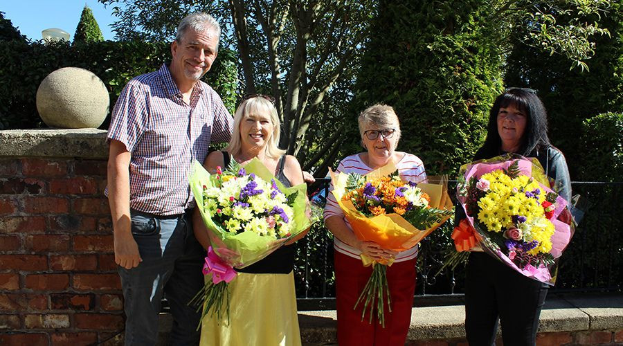 Four award-winners standing in a row holing a large bouquet of flowers