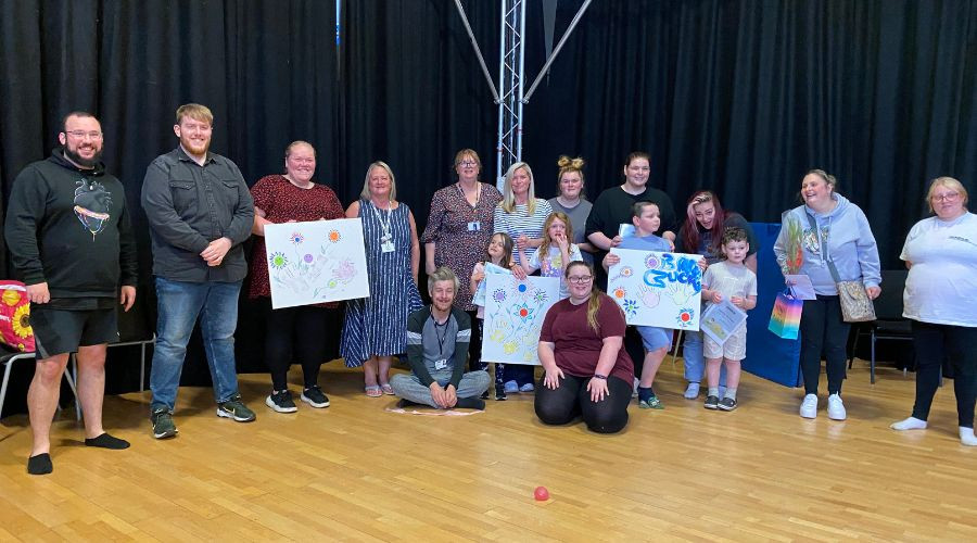 SEND team, parents and children standing in a row displaying handmade artwork