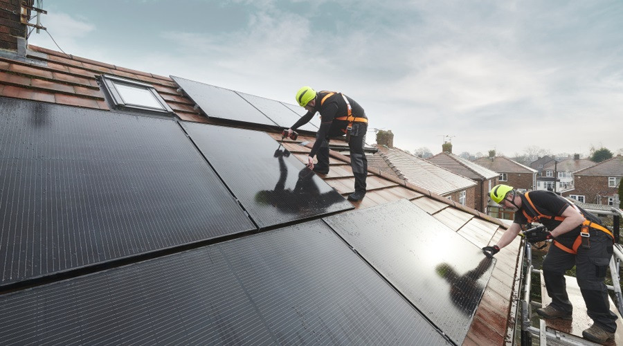 two workmen on a roof installing solar panels