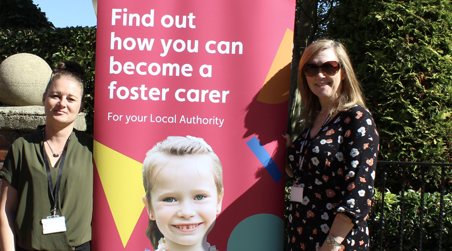 Two Foster 4 staff members stand either side of a banner