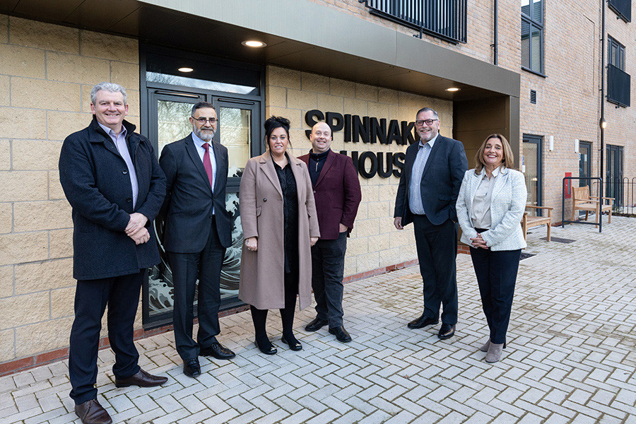 Picture of six people standing outside spinnaker house smiling to camera