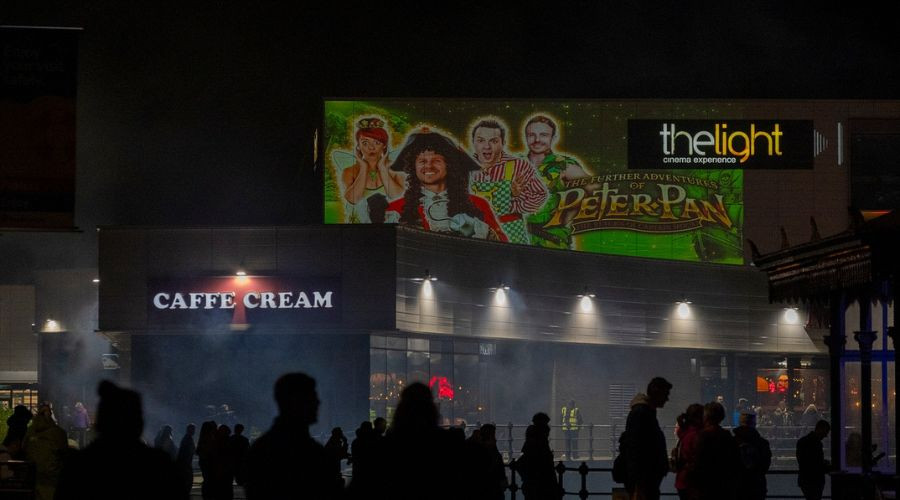 Photo of a silhouette of crowds in front of a huge projection 