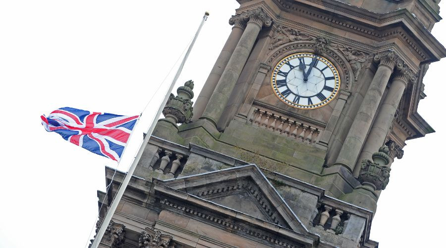 Photo of the flag lowered and clock at 11am