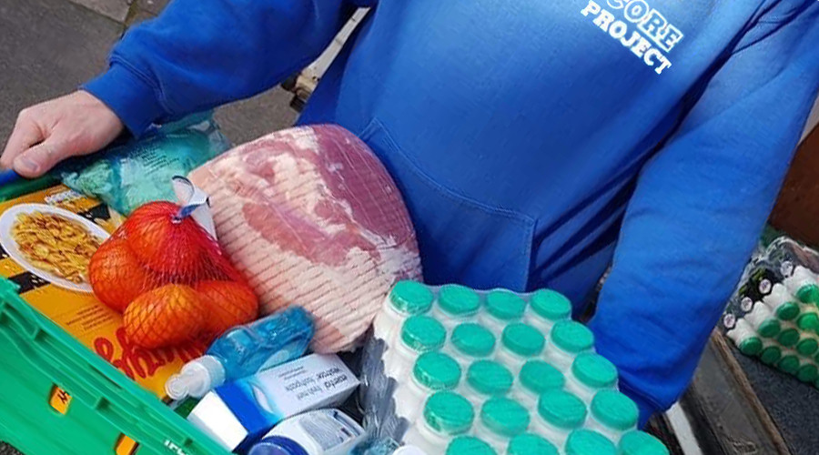 picture of a person in a blue jumper holding a food hamper