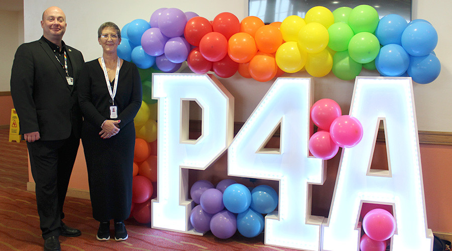 The Leader of Wirral Council and the Chair of Parent Carer Participation Wirral standing next to a preparation for adulthood illuminated sign. The sign is covered in balloons.