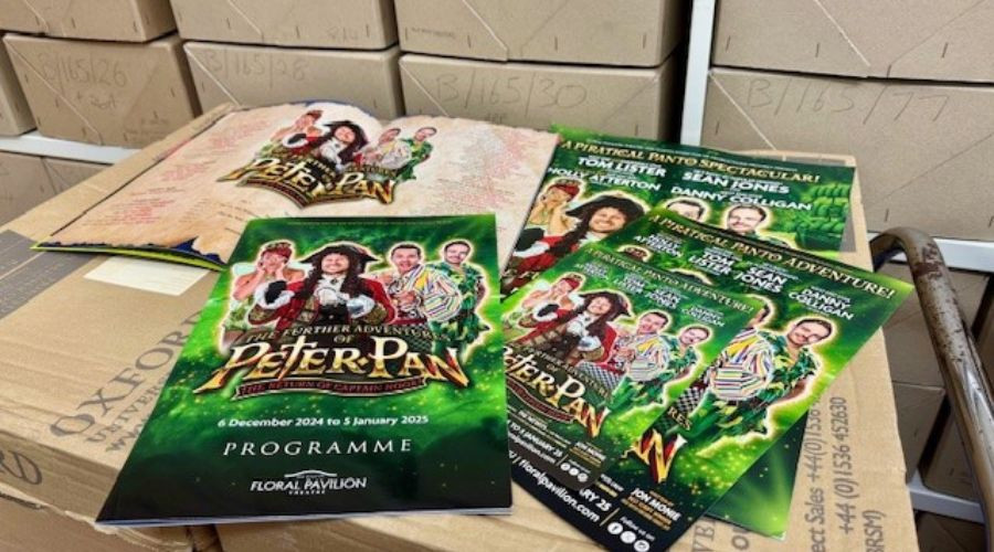 A photo of the panto programme and some flyers on a box in Wirral archive