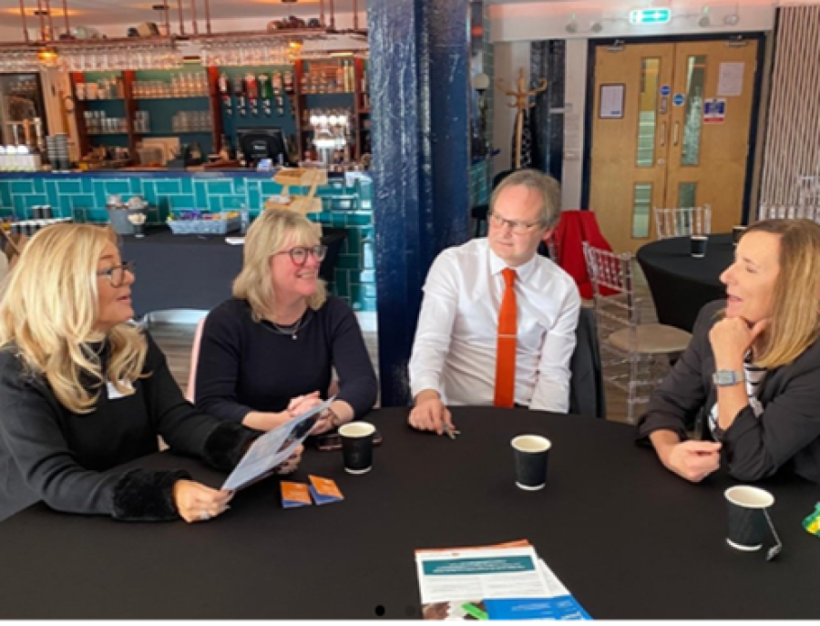 A photo of four people around a table giving business advice