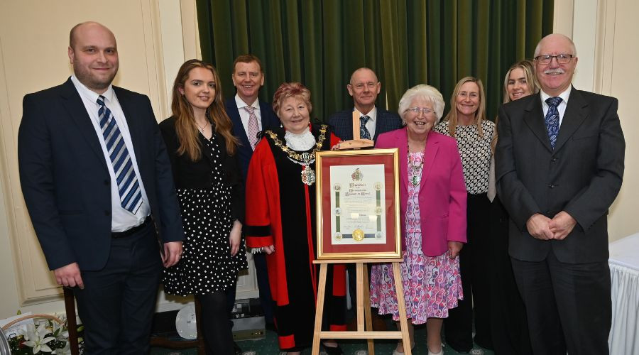 Photograph of the Mayor and Mayoress of Wirral congratulating the YMCA Wirral team alongside their new Freedom of the Borough Commemorative Scroll