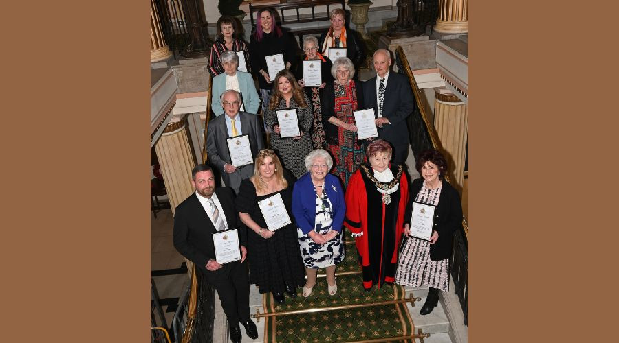 Photo of Wirral Award recipients holding their certificates with the Mayor on the town hall staircase