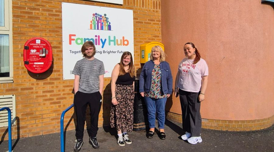4 people standing outside of the St James Centre in front of a Family Hub sign