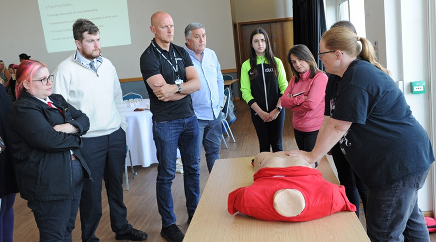 Volunteers see a demonstration of the bleed control kits in action