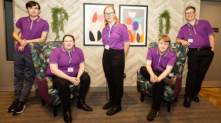 A group students wearing purple Premier Inn polo shirts and black trousers.