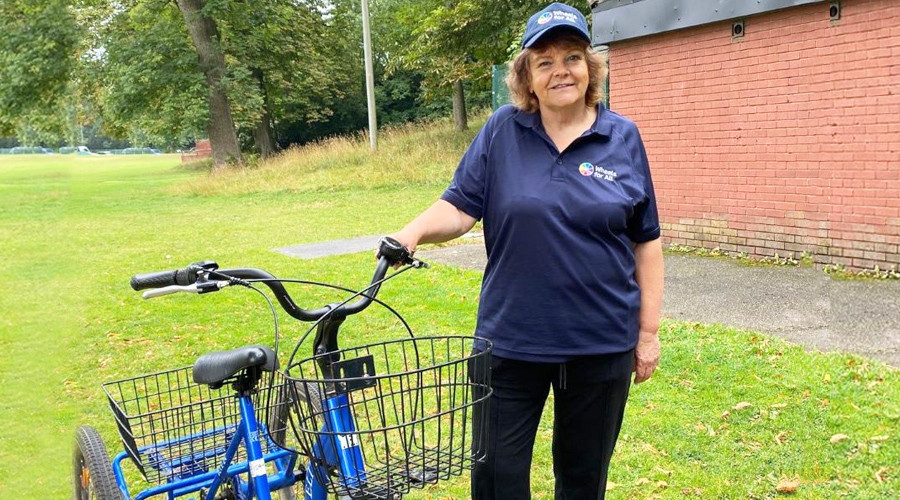 erson with an accessible adult tricycle from 'Wheels for All', promoting inclusive cycling.
