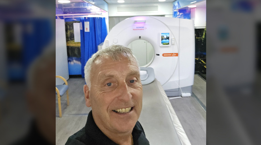 selfie style picture of a man standing in front of a ct scanning machine