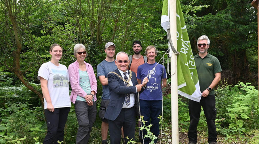 Group of people with Wirral's Mayor Brian Kenny holding a Green Flag