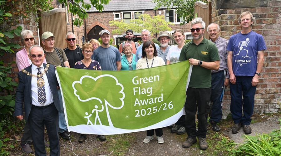Group of people with Wirral's Mayor Brian Kenny holding a Green Flag