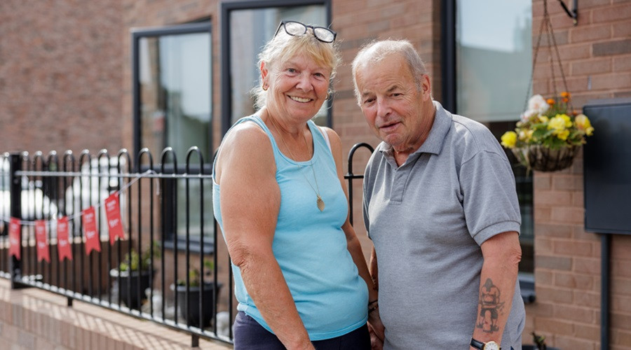 An older couple outside their new home in New Ferry