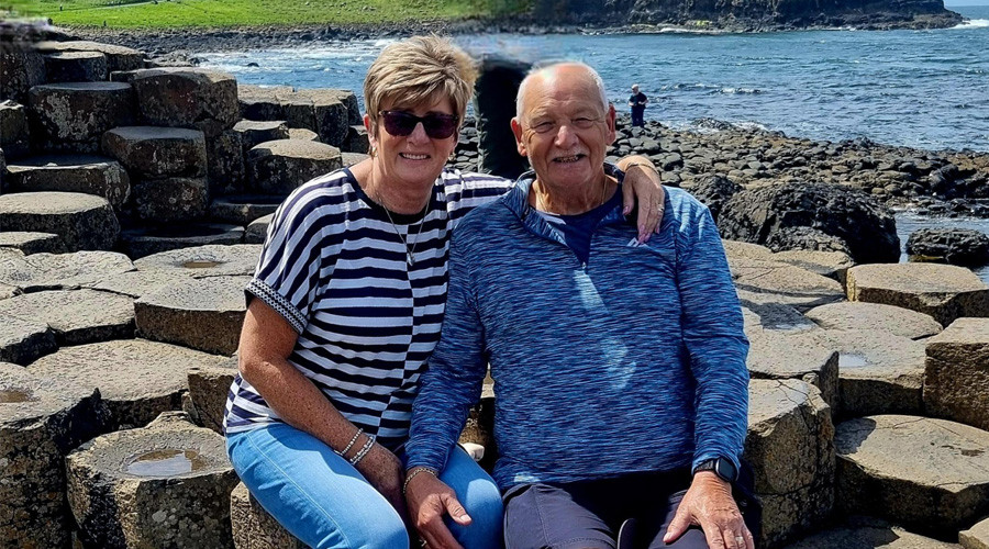 Senior couple sitting down on the basalt columns, Giants Causeway, Causeway Coast, County Antrim, Northern Ireland
