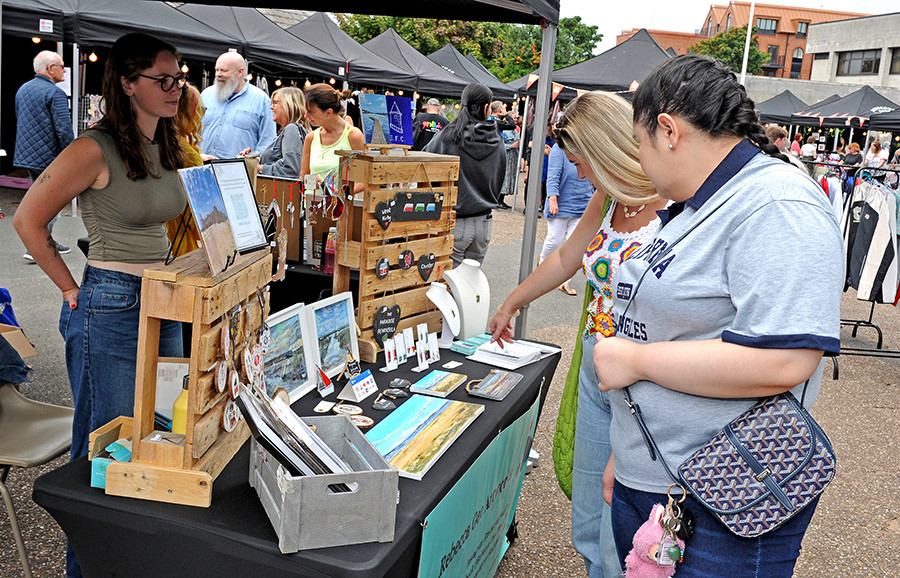 a stall holder and shoppers looking at goods for sale at a Wirral Youth Market event
