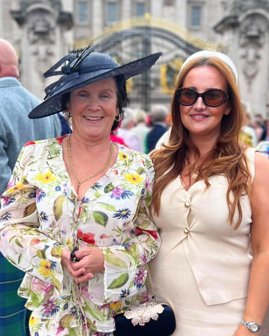 Julie pictured smiling next to another lady outside Buckingham Palace
