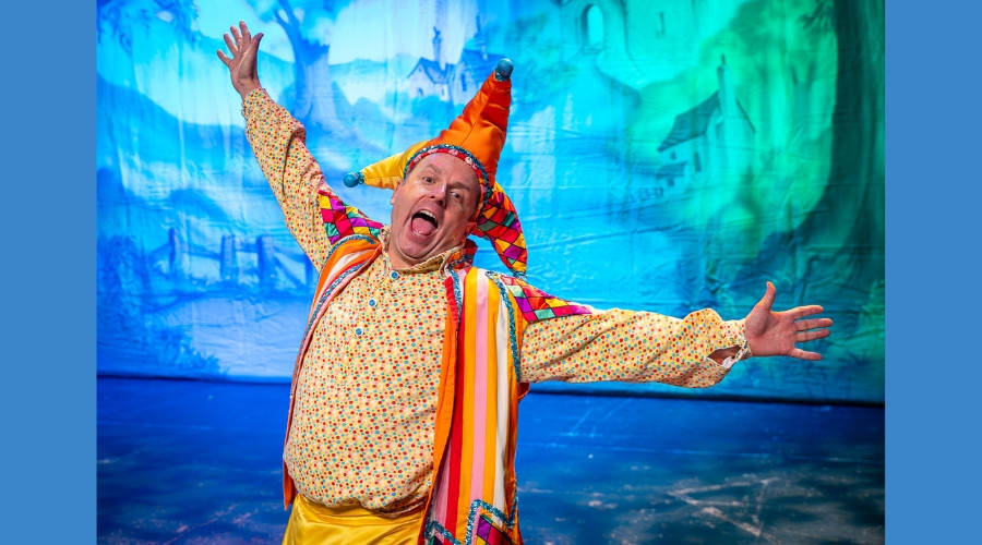 Photo of Sean Jones on stage with his arms open wide dressed in the costume of Lester the Jester