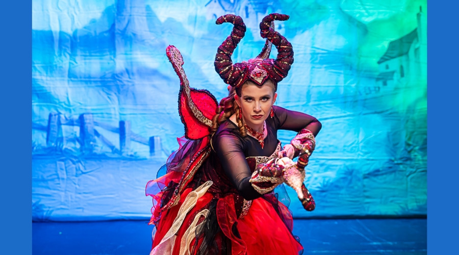 Photo of Amy Perry on stage dressed in the costume of Carabosse and pointing her lance