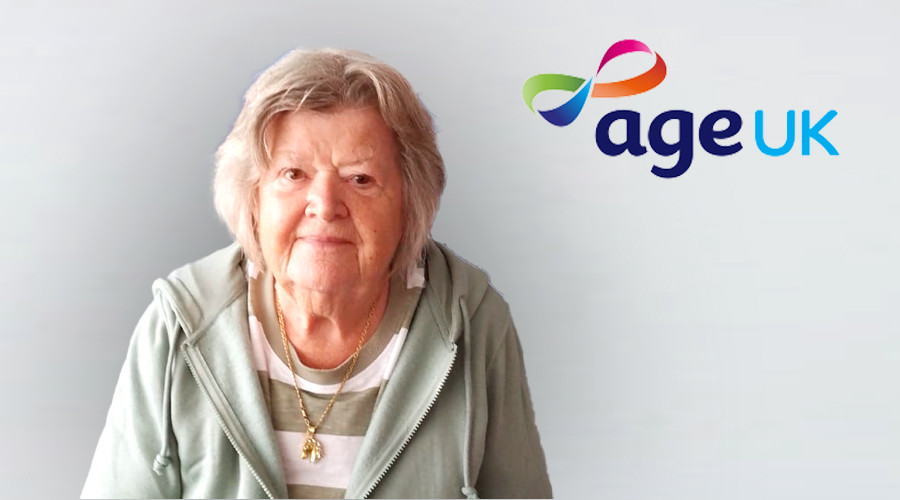 Picture of a lady in her 70s smiling to camera with the Age UK logo next to her