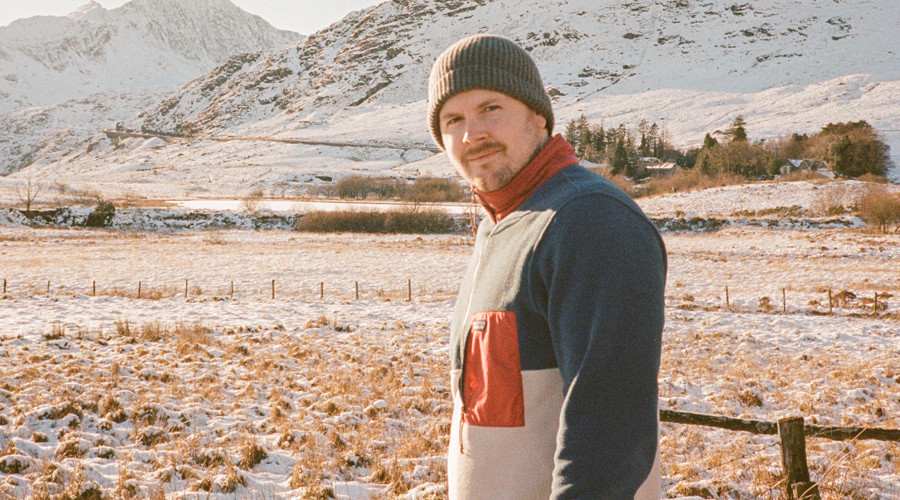 Scott in foreground wearing winter wear with mountains in background covered in snow